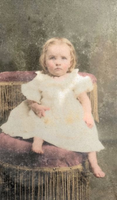 Restored and colorized (AI-assisted); faces are the original photo, colours are a best guess. Emma Lee Martin at three years old — carte de visite, Gallatin, Tennessee.