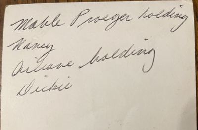Back of the print: handwritten caption "Mable Proeger holding Nancy / Aileane holding Dickie" — photograph courtesy of Sheryl (cousin) · Sheryl: "grandma holding little [Dickie] … and Mable holding mom"; the family called Richard Jr. "little Dickie"