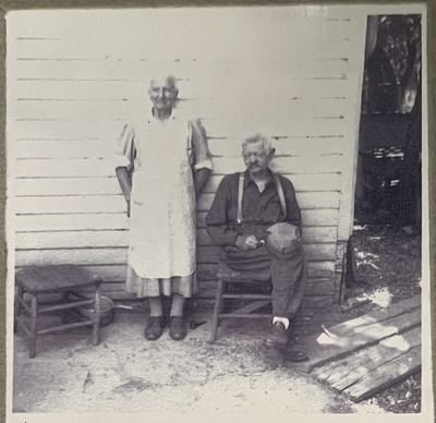 Julia and Mons Selland in old age, outside a clapboard house