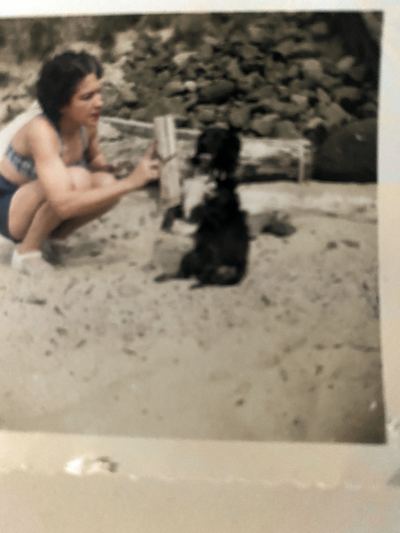 Restored and colorized (AI-assisted); faces are the original photo, colours are a best guess. Aileane with the dog Dugan, at a beach.